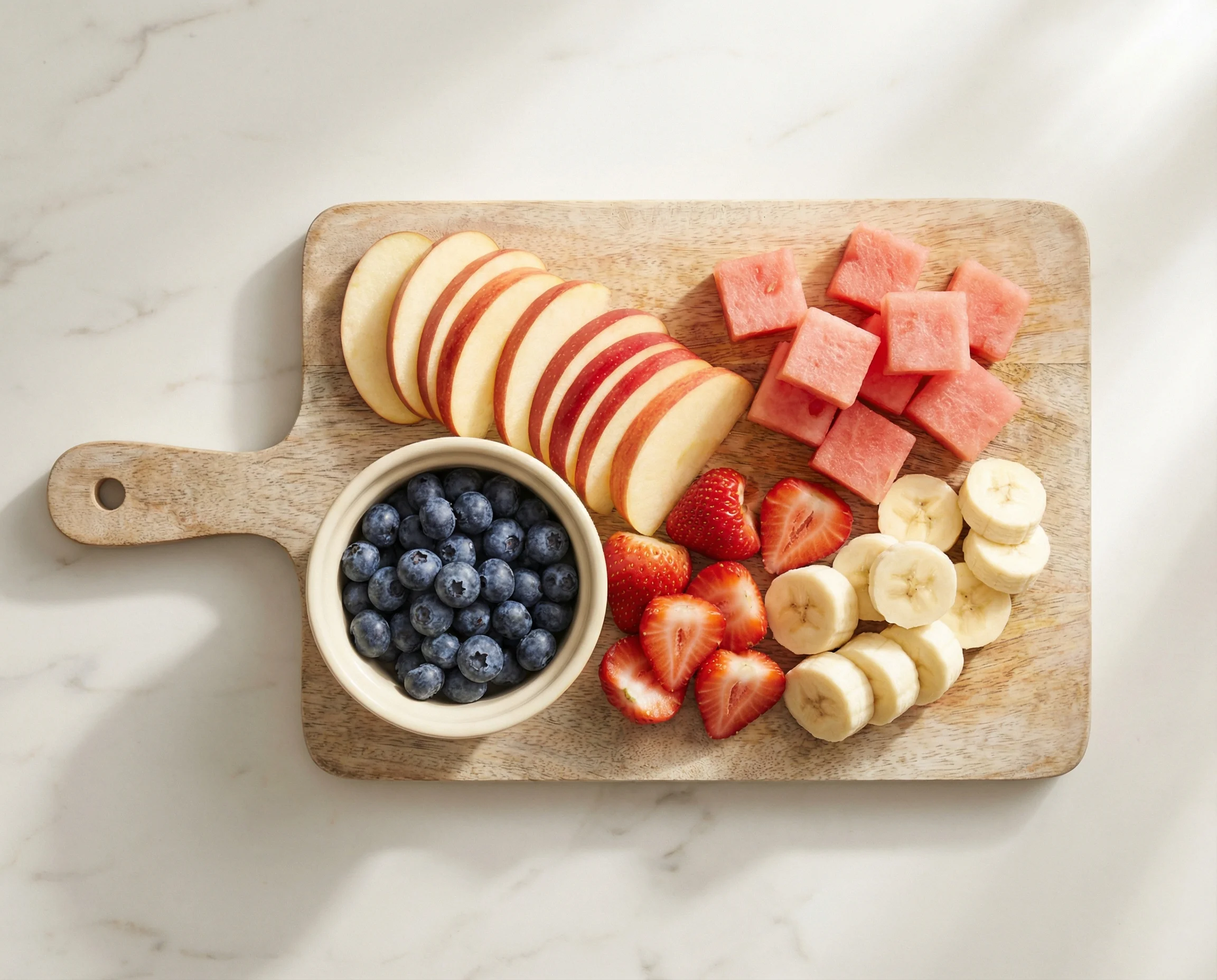 Array of safe fruits for dogs including apples, blueberries, and watermelon on a clean cutting board